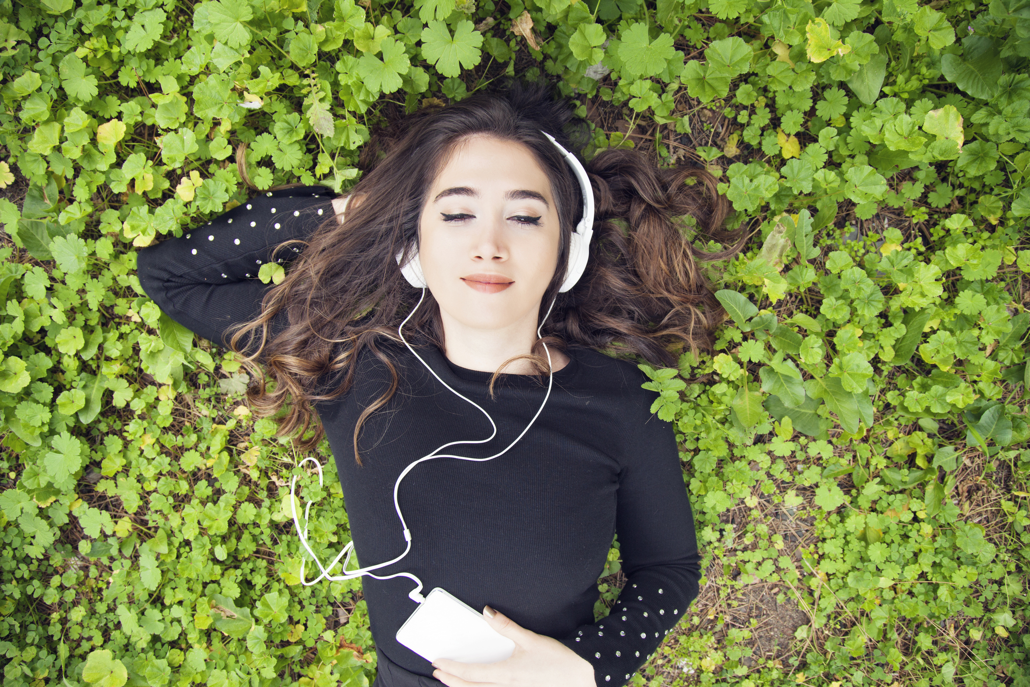 Portrait of Young woman listening to music on grass