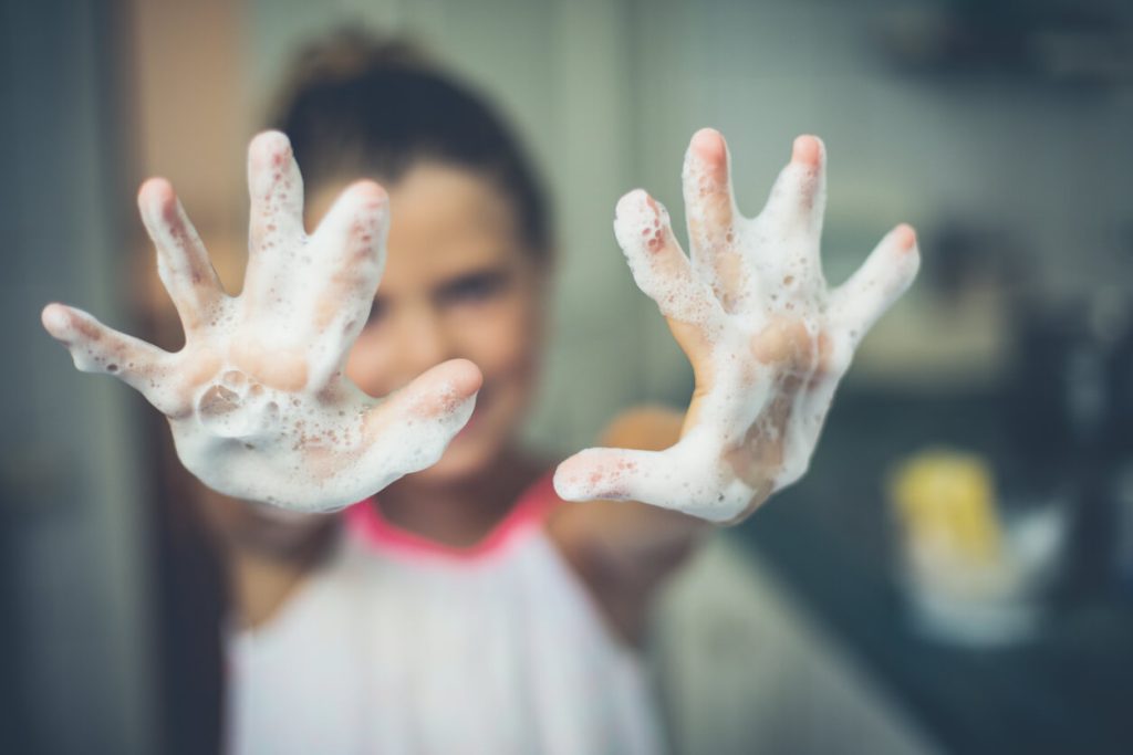A girl holding out her hands slathered in soap