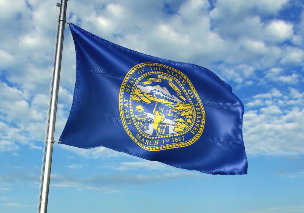 Nebraska state of United States flag on flagpole waving cloudy sky Nebraska state of United States flag on flagpole waving cloudy sky