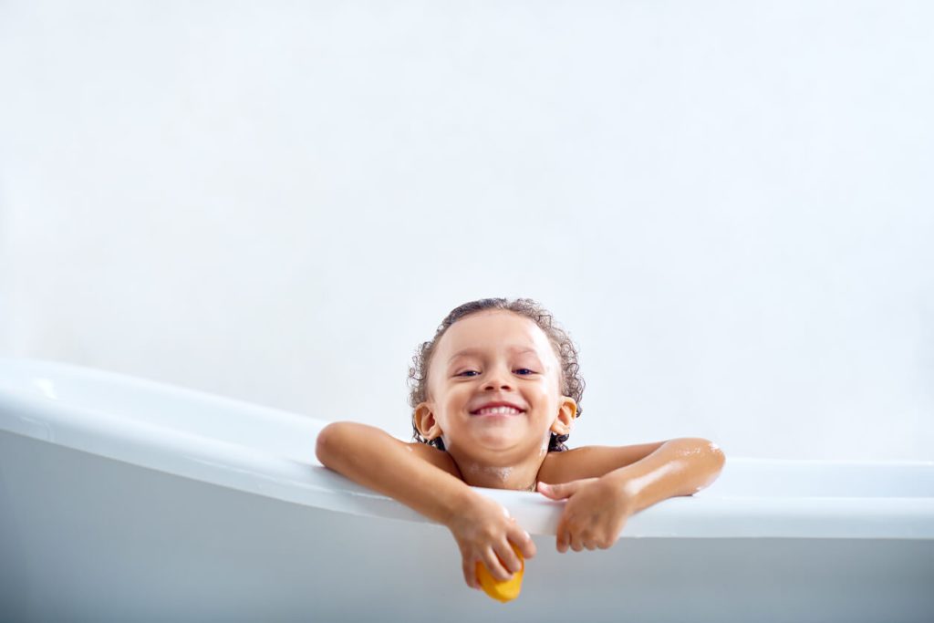 A little kid in a bath smiling