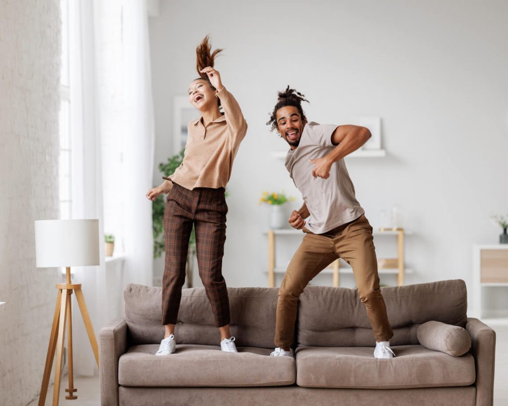 A couple dancing in celebration on their couch