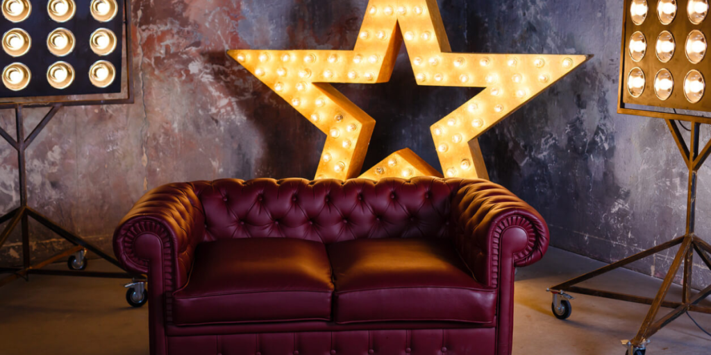 A red leather couch surrounded by theatre lights and a light-up star in the background